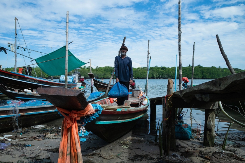 A man standing on a boat holding a bag filled with crabs.